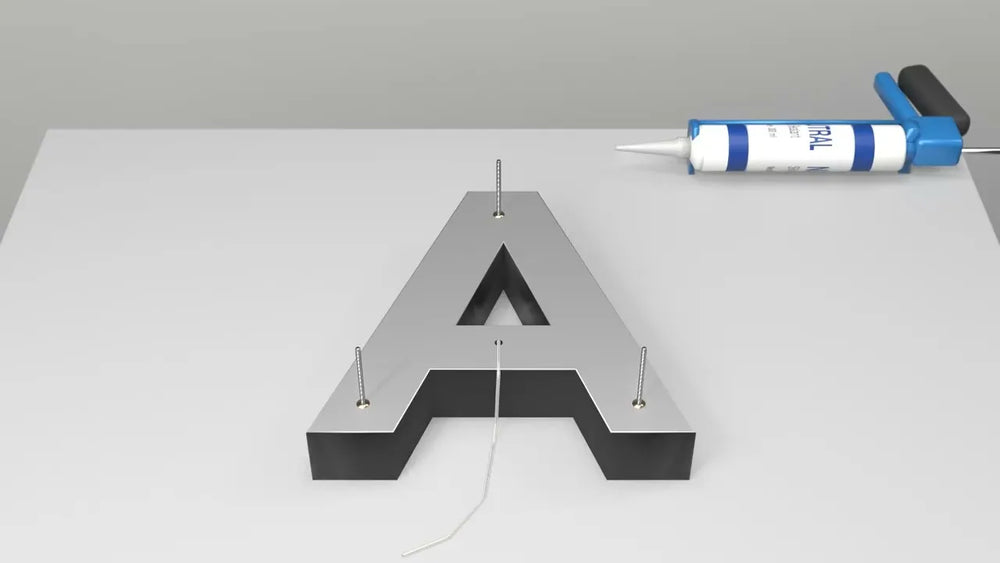 Back of a channel letter with threaded mounting rods, the wire lead and a tube of neutral-cure silicone
