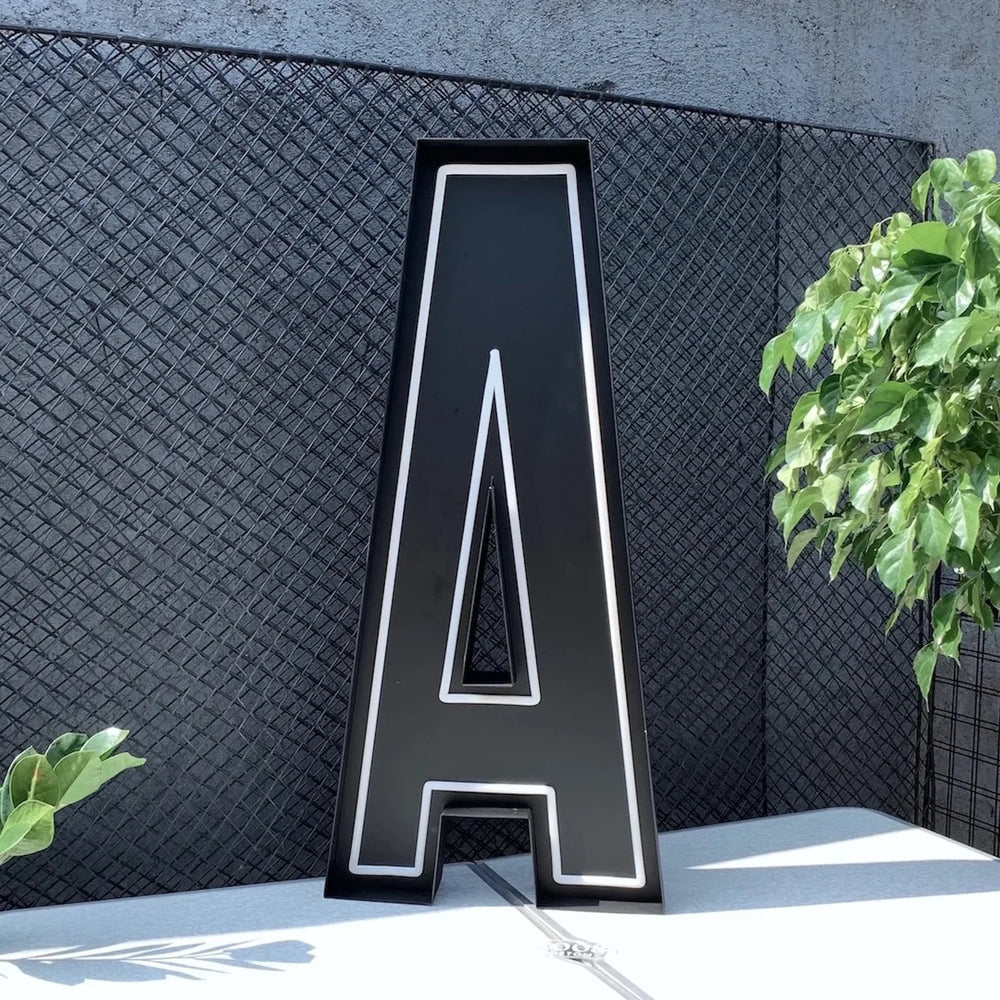 Large fabricated channel letter photographed beside a fence, showing the scale a quote has to account for