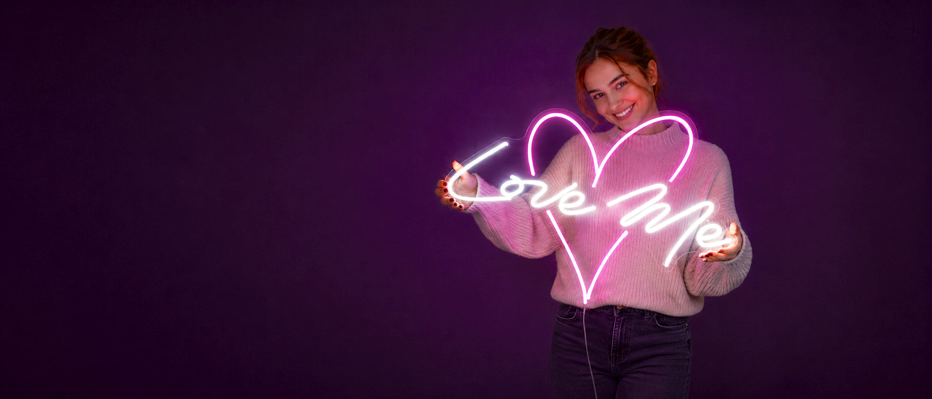 Custom LED flex neon sign — smiling woman holding a pink Love Me heart neon light on a purple background