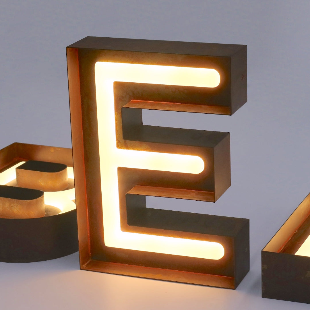 Custom open face exposed channel letter E with warm white LED neon lighting and dark metal returns