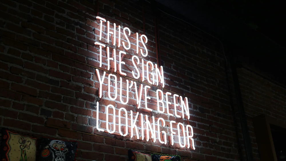 Real glass neon sign mounted on an exposed brick wall