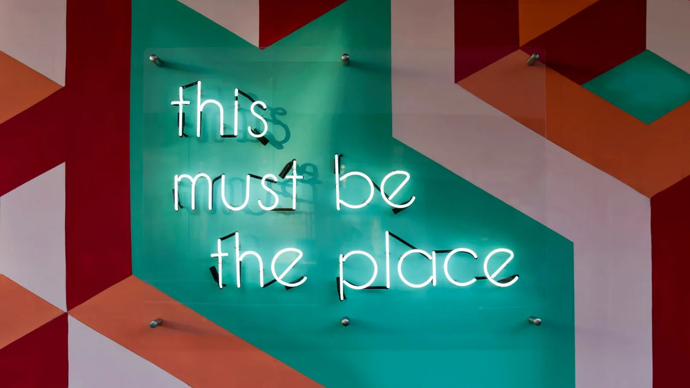 Real glass neon sign mounted on a patterned wall, seen at an angle